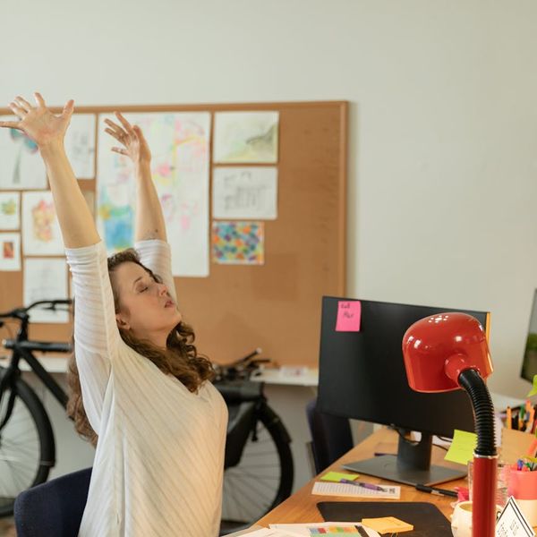 A person gently stretching at their workplace desk.